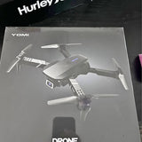Foldable gray drone in retail box, propellers visible