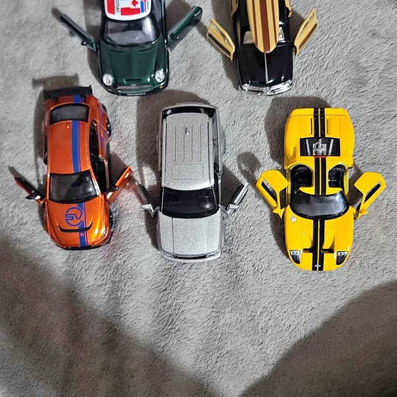 Diecast cars collection with four vehicles in green, orange, gray, and yellow.