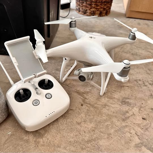White quadcopter drone with four rotors and handheld controller