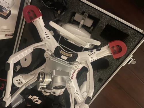 White quadcopter drone with red propeller guards, inside open hard case
