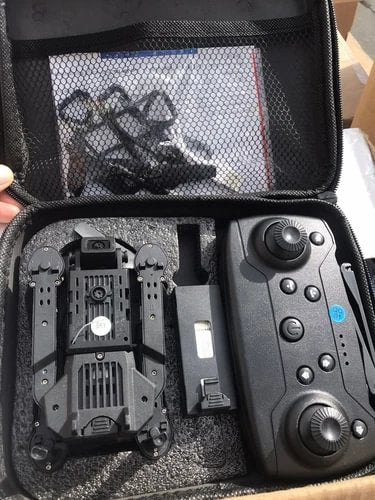 Foldable quadcopter drone and remote controller inside open hard case, showing prop arms