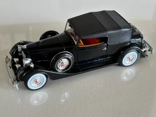 Black diecast vintage model car with open grille and whitewall wheels, chrome details