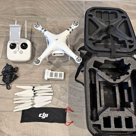 White DJI Phantom quadcopter drone with controller, batteries, propellers, and carrying case.