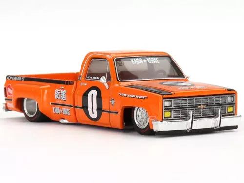 Orange diecast pickup truck with black racing stripe, front grille and number 0 on door.