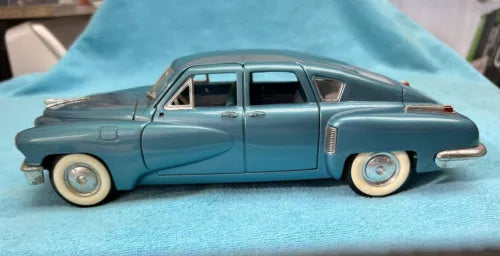 Blue diecast model car, 1:18 scale, side view with chrome details