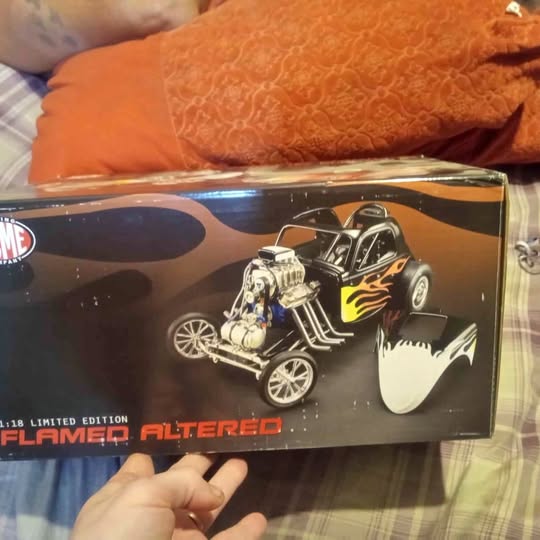 Diecast model vehicle in display box, black with flame graphics and chrome engine