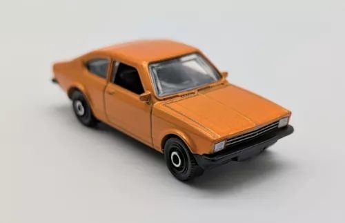 Orange 1:64 diecast coupe car with black grille, bumper, and wheels
