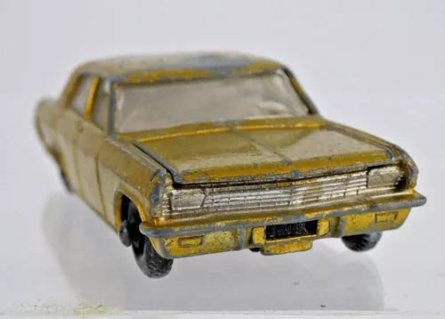 Vintage diecast toy car, olive yellow, front grille and bumper details visible