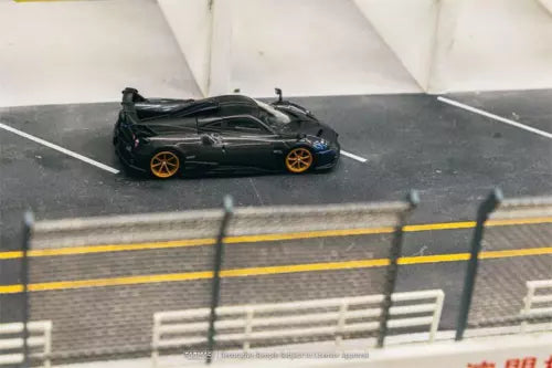 Diecast model car of a dark green Pagani with gold wheels, front three-quarter view
