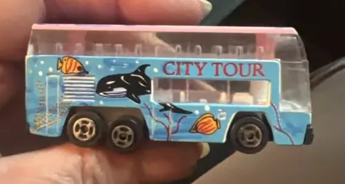 Diecast city tour bus toy with whale and seashell graphics, City Tour text, in clear box