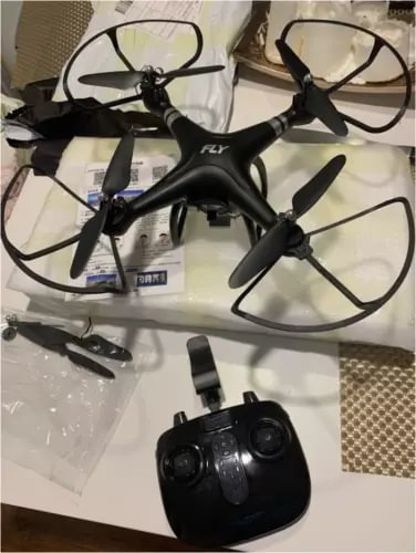 Black RC quadcopter drone with four propellers and attached camera, plus handheld controller