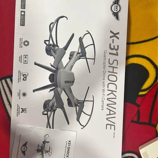 White quadcopter drone with four prop arms and foldable landing legs on a box
