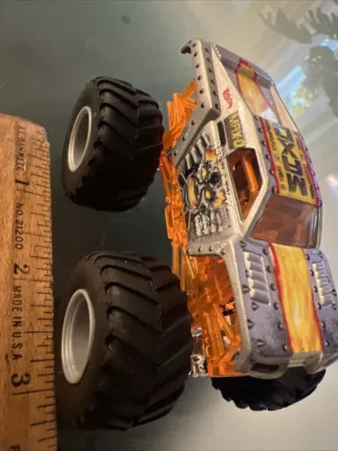 Orange and white diecast monster truck with black tires and exposed roll cage