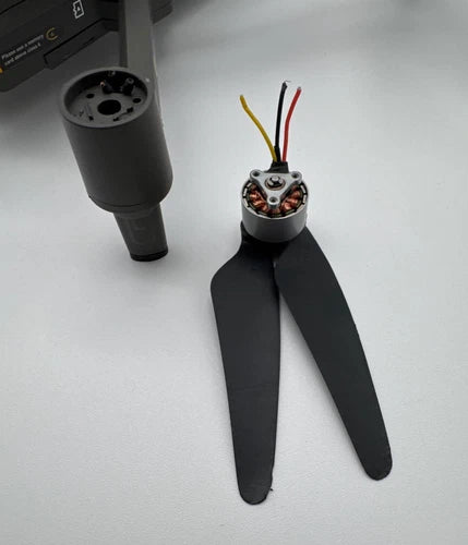 Black quadcopter drone with three-blade propellers and exposed wiring on top