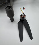 Black quadcopter drone with three-blade propellers and exposed wiring on top