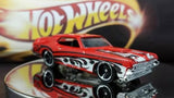 Red 1:64 scale diecast model car with black wheels and flame-style decals