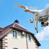 Real estate drone with camera hovering near house roof.