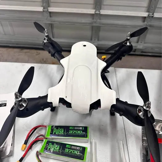 Camera quadcopter drone, white body, four black propellers, visible green controller screens