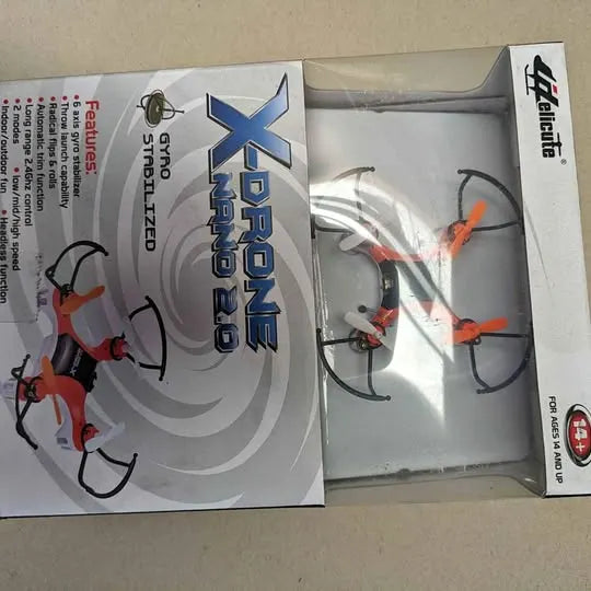 Quadcopter drone with orange prop guards in open retail box