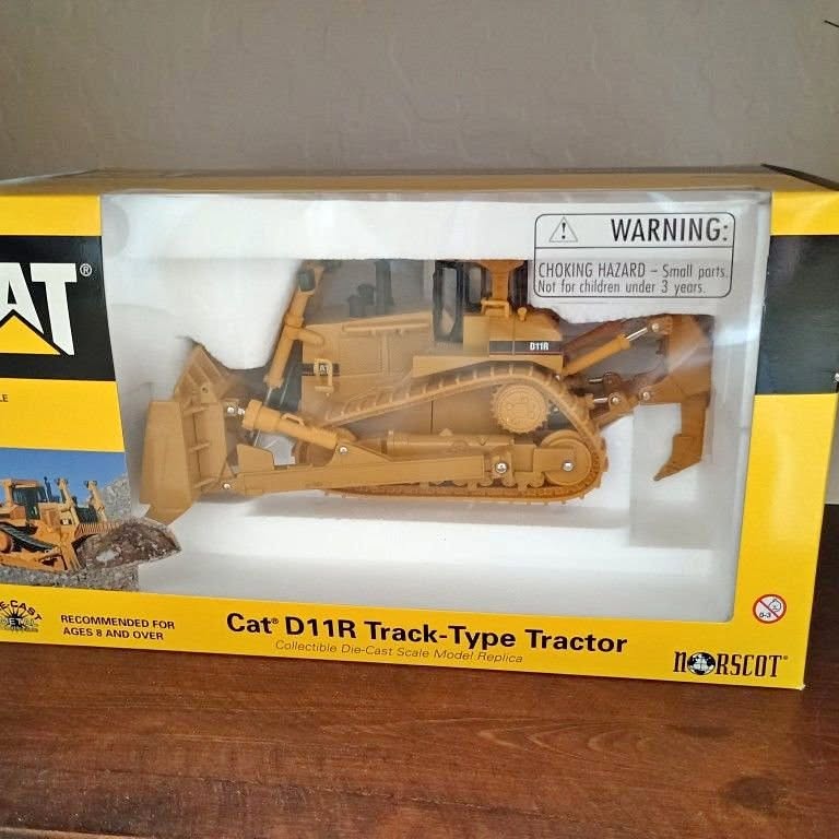 Yellow diecast track-type tractor toy in clear blister packaging