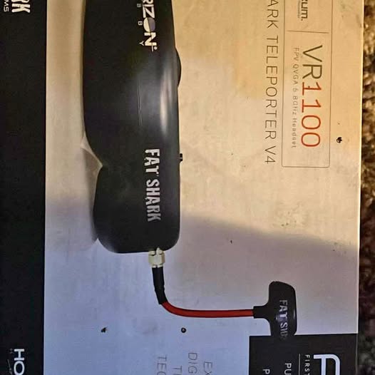 Handheld drone controller with red and black cables, black device