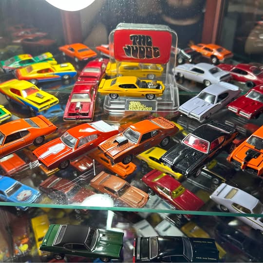 Assorted diecast toy cars in various colors, with visible hoods and bumpers