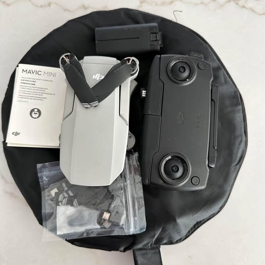 Folding grey DJI drone with controller module and charging accessories in box