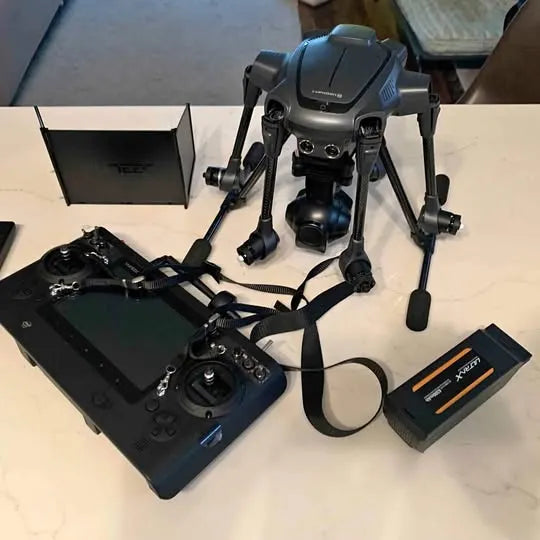 Gray folding drone with controller, battery, and accessories in a kit layout