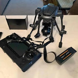 Gray folding drone with controller, battery, and accessories in a kit layout