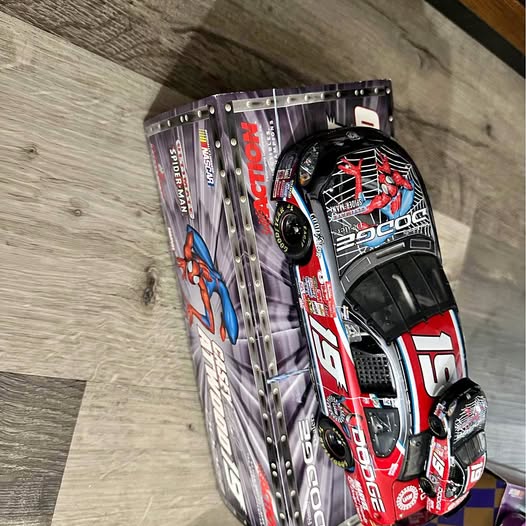 Diecast race car in retail box, dark red and black with sponsor decals