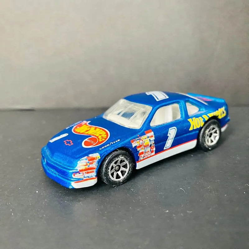Dark blue diecast stock car with #7 decals and white side stripe, front three-quarter view