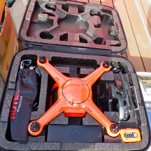 Orange quadcopter drone in hard case with controller and tools
