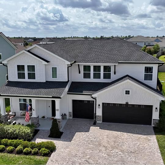 Drone photos and videos: white two-story house with dark roof and two-car garage