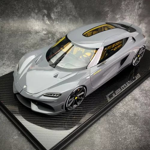 Gray 1:12 diecast model car with black and gold accents on display base