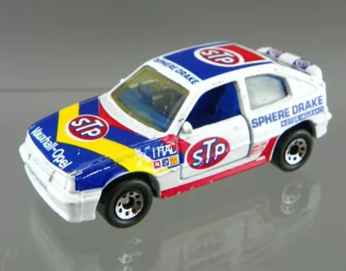 Vintage diecast rally car, white with blue and red stripes, STP and Sphere Drake logos, 1/57 scale