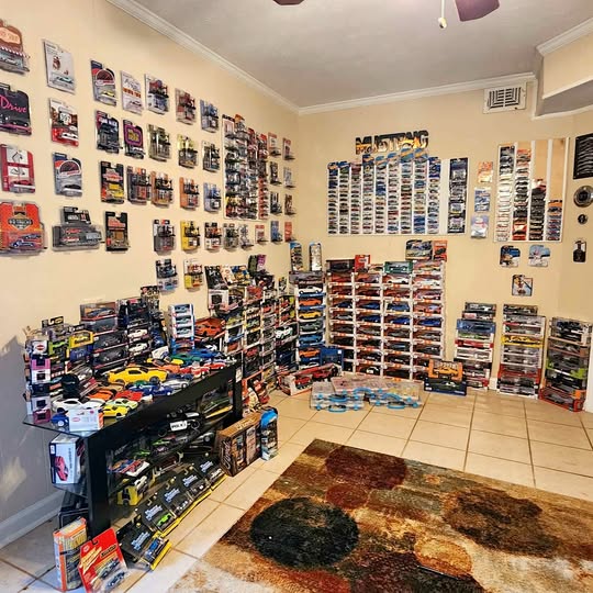 Diecast model car collection display with boxed cars on shelves and wall hooks