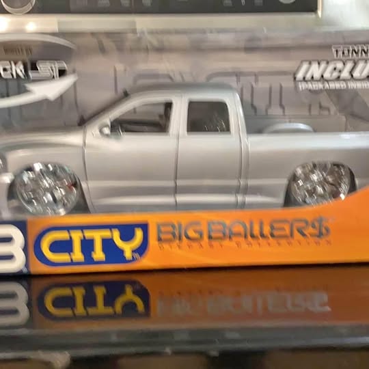 Silver diecast pickup truck model in box, visible cab and wheels