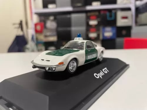 Diecast police model car, white with green stripe, on black display base