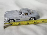 1:36 die-cast toy car, silver coupe beside measuring ruler