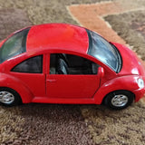 Volkswagen New Beetle diecast model car, red with black windows and silver wheels