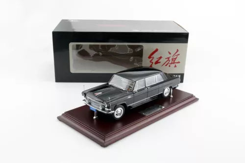Diecast limousine model in dark gray on display base, inside a box