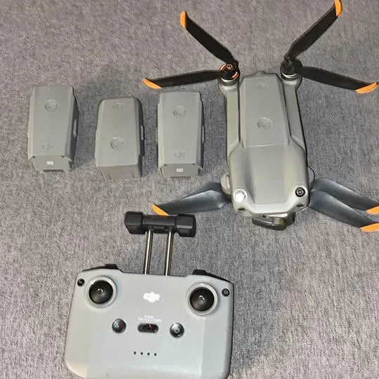 DJi drone with remote controller and multiple flight batteries, gray
