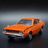 Orange 1:64 scale diecast model car, front three-quarter view, classic sedan