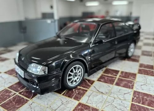 Black diecast sedan model car, front-left view with detailed headlights and wheels
