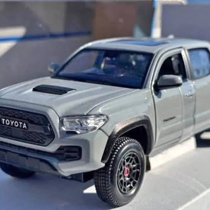 Silver diecast pickup truck model with black hood scoop and off-road tires