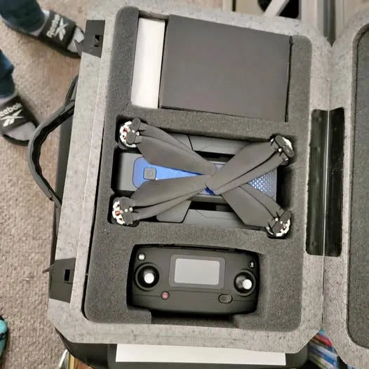 Gray quadcopter drone with four propellers and controller in foam case