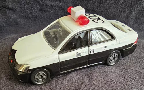 Cream and black 1:64 diecast toy car with red roof light