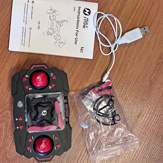 RC drone controller with red circular joysticks and wrist strap, with USB cable