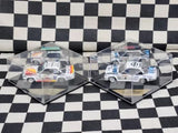 Two 1:43 rally diecast model cars in clear display boxes, white with orange and blue.