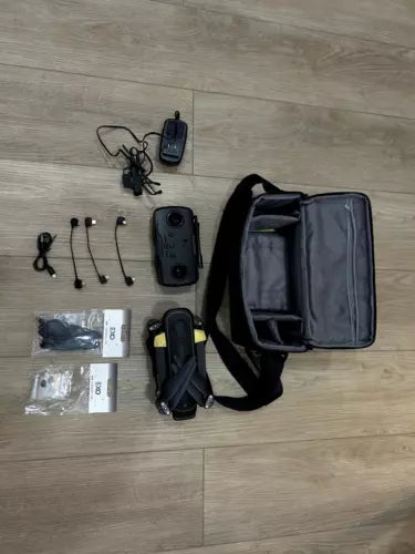Drone kit with black drone, remote controller, spare parts, and carry bag